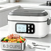 A white electric heating lunch box with a digital timer sits next to a stainless steel meal container and silverware.