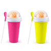 A pink DIY slushy maker cup filled with orange fruit, next to a yellow version.
