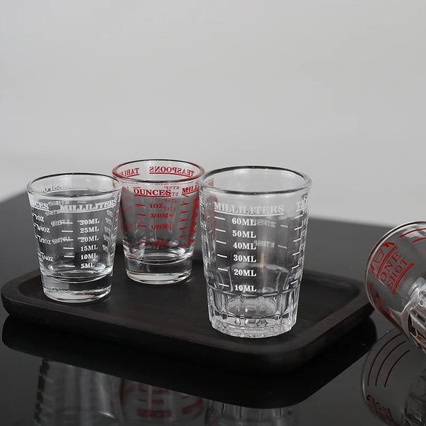 Ein Set klarer Glasmessbecher mit Volumenmarkierungen auf einem schwarzen Tablett.
