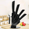 A black ceramic multi-use kitchen knife set displayed on a wooden cutting board with fresh peppers.