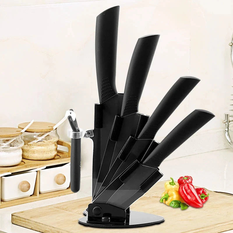 A black ceramic multi-use kitchen knife set displayed on a wooden cutting board with fresh peppers.