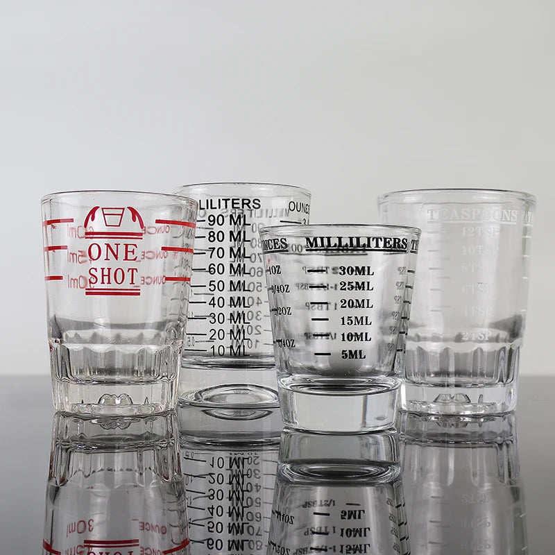 A collection of clear glass measuring cups with various volume markings, including shot glasses and larger liquid measures.