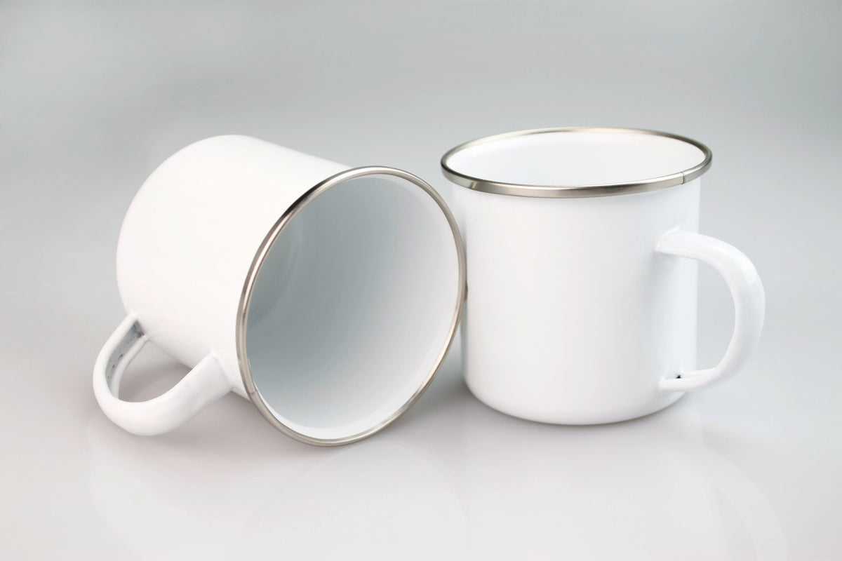 A white enamel mug with a silver rim and handle is shown against a light gray background.