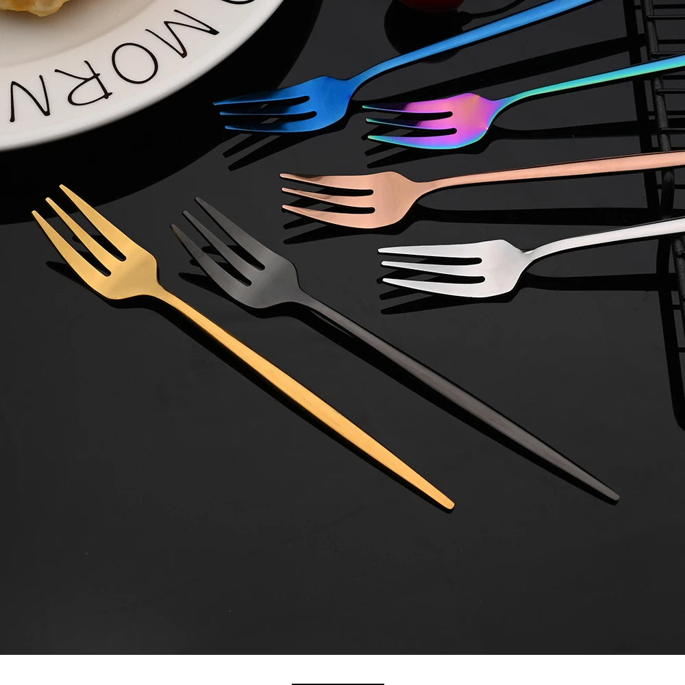 A collection of various colored stainless steel cutlery including forks and knives arranged on a dark surface.