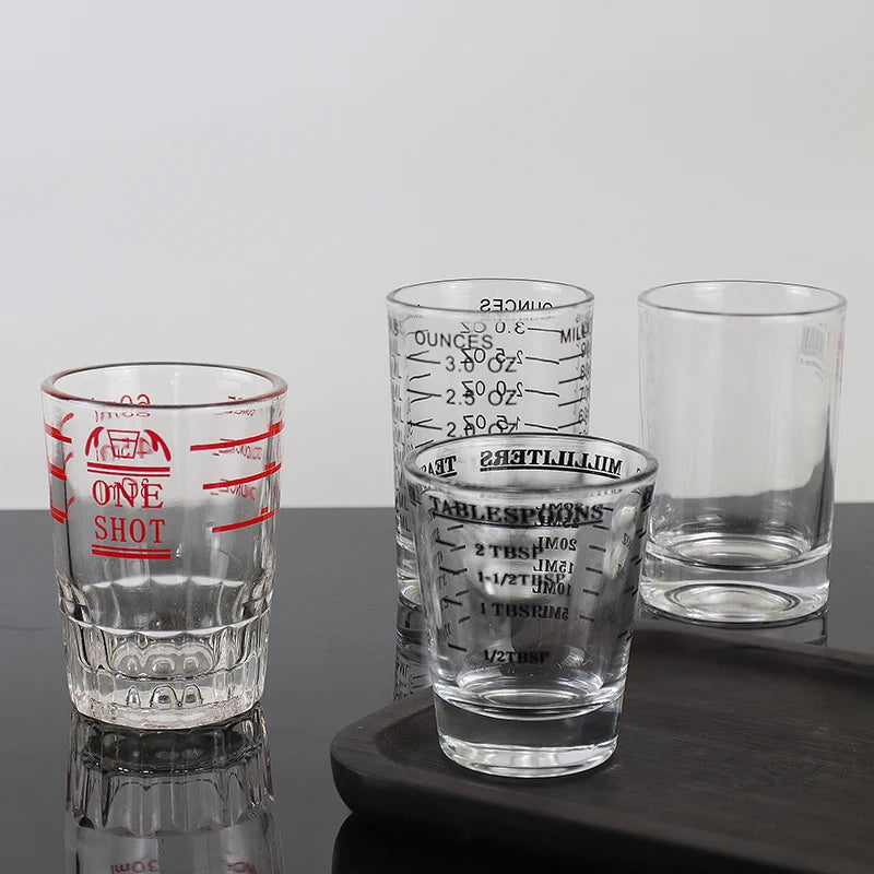 A set of clear glass measuring cups with etched volume markings for espresso and kitchen use.