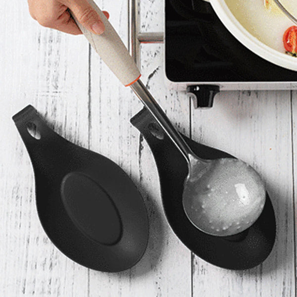 Eine Hand benutzt einen Silikon-Utensilienhalter mit einem Metalllöffel, um Essen in einer schwarzen Organizer-Schale zu rühr