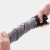 A hand is holding a gray heat resistant silicone oven mitt with textured grips.