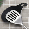 A silver silicone spatula rests on a black silicone utensil holder against a light checkered background.