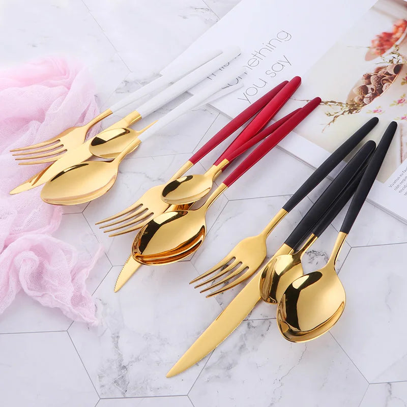 A set of elegant stainless steel flatware including forks and knives displayed on a white marble surface.