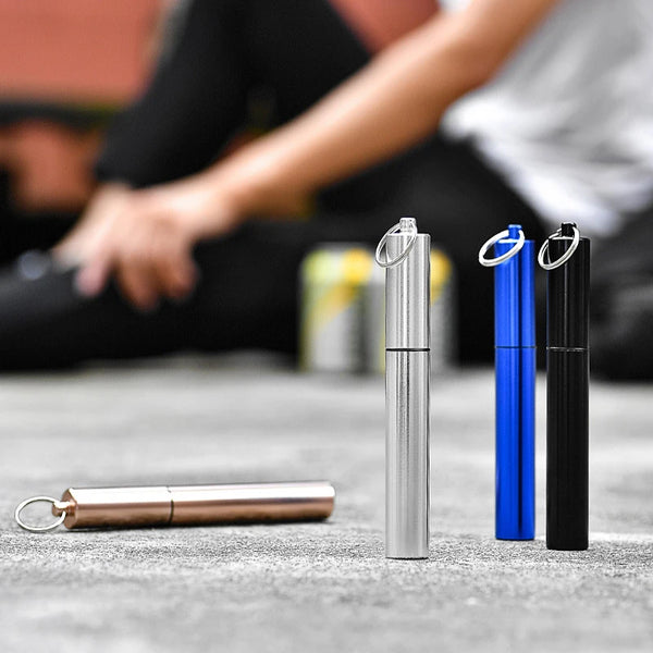 A set of stainless steel telescopic drinking straws in silver and blue with cleaning brushes displayed on a gray surface.
