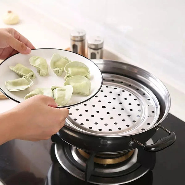 Hände legen grüne Dumplings in ein Mehrgrößen-Edelstahl-Kochgefäß.