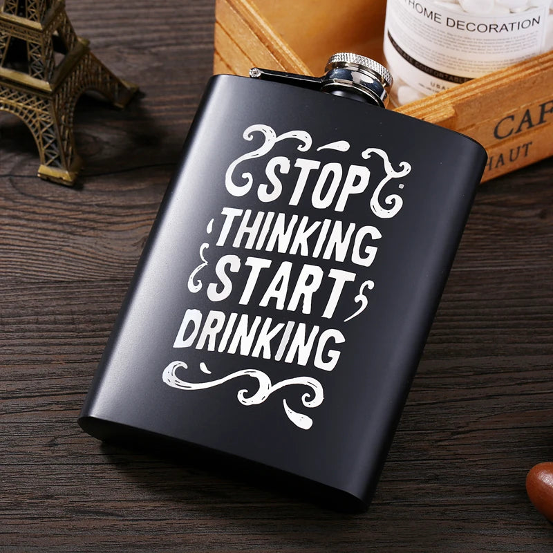 A black laser engraved stainless steel hip flask with white text that reads Stop Thinking Start Drinking