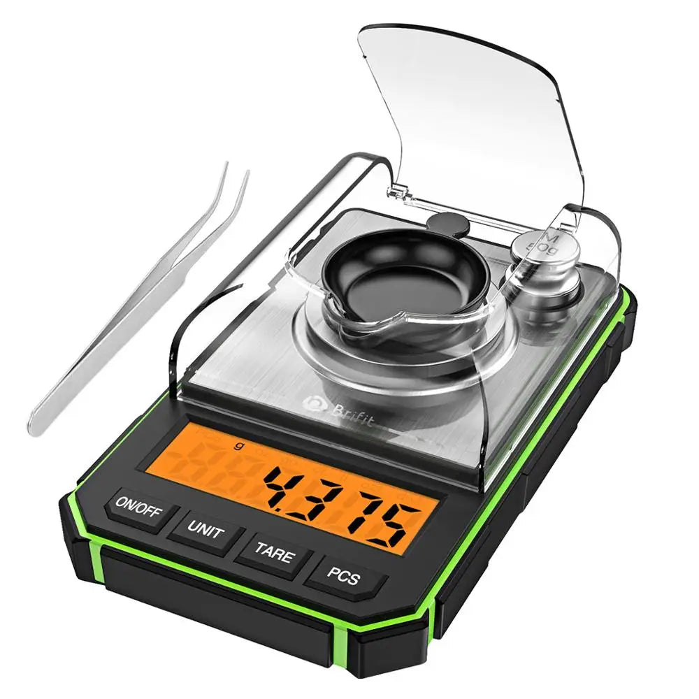 A black digital scale with a clear lid and a stainless steel spatula is shown on a white background.