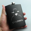 A black laser engraved stainless steel hip flask with a silhouette of a hat and face on the front