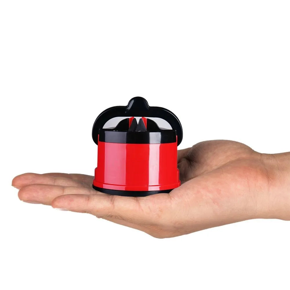 A red and black suction knife sharpener is held in a person's hand.
