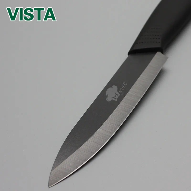 A close-up view of a black ceramic multi-use kitchen knife with a silver blade and a visible brand mark.