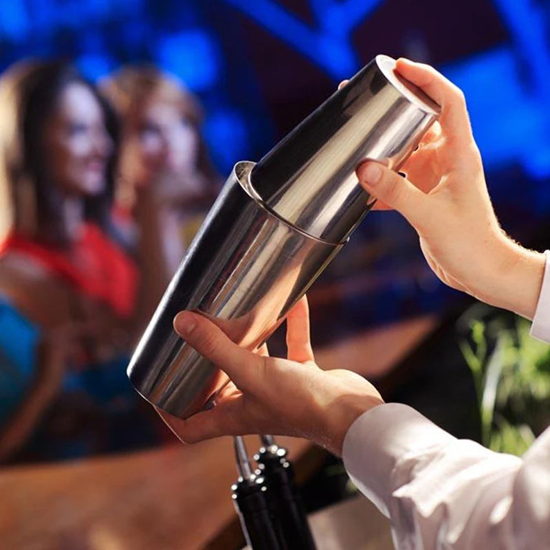 A person holds a professional stainless steel cocktail shaker, preparing to mix a drink.