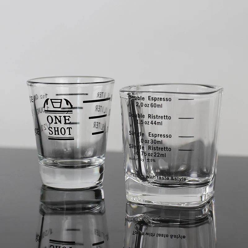 Two clear glass measuring cups with etched markings for espresso and kitchen use