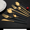 A set of gold-colored stainless steel cutlery including spoons and forks displayed on a dark surface.