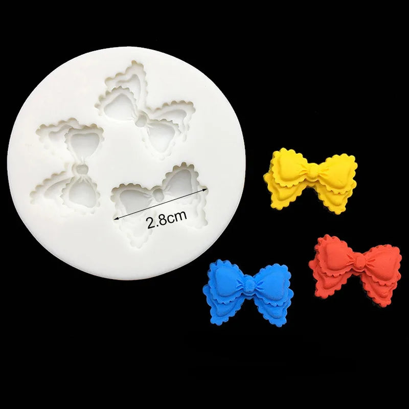 White silicone baking molds with decorative shapes for chocolate cupcakes, including a bow in yellow, orange, and blue.
