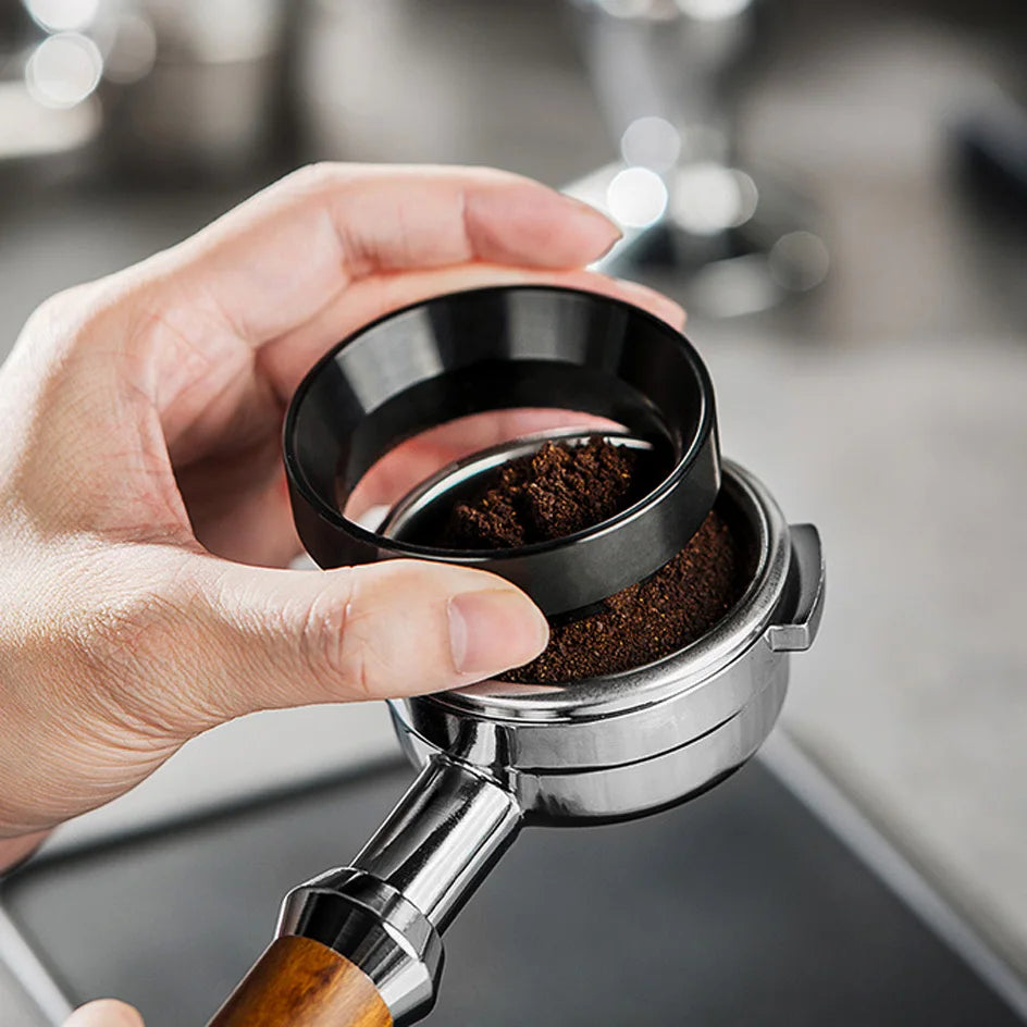 A hand holds a stainless steel espresso coffee stirrer tool, preparing to stir coffee grounds in a filter.