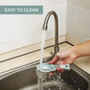 A hand is using a precision fish scale scraper and cleaning brush set to clean a kitchen sink.