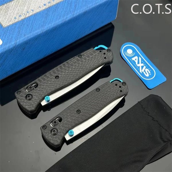 Ein Paar schwarze faltbare Taschenmesser mit silbernen Klingen und blauen Akzenten auf dunkler Oberfläche.