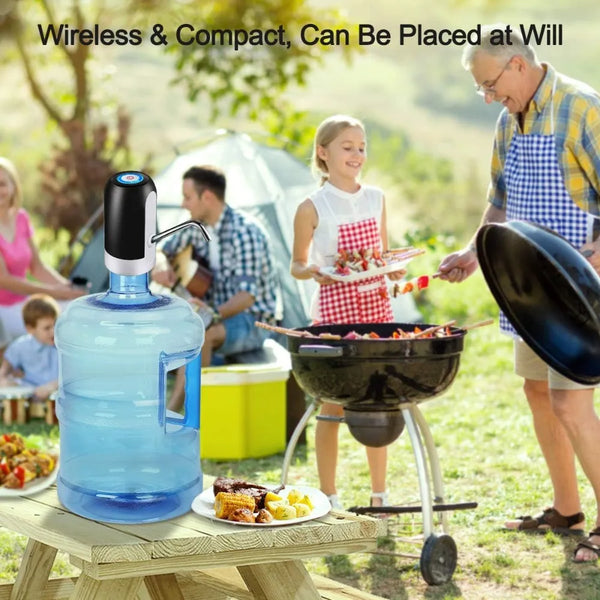 A blue automatic electric water dispenser pump is placed on a wooden table outdoors near a person grilling food.