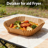 A brown paper liner holds roasted vegetables in an air fryer basket.