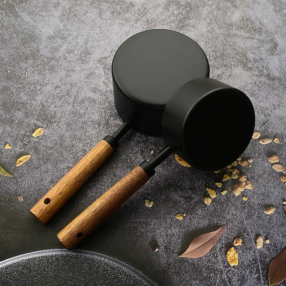 A black stainless steel measuring set with wooden handles is displayed on a dark gray surface.