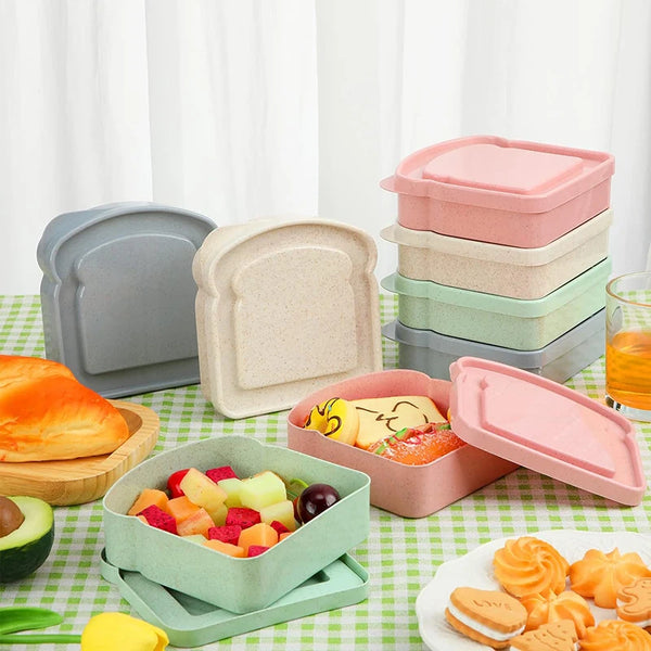 Eine Sammlung wiederverwendbarer rosa und grüner Mikrowellen-Sandwichbehälter und Lebensmittel auf einer grün karierten Matte