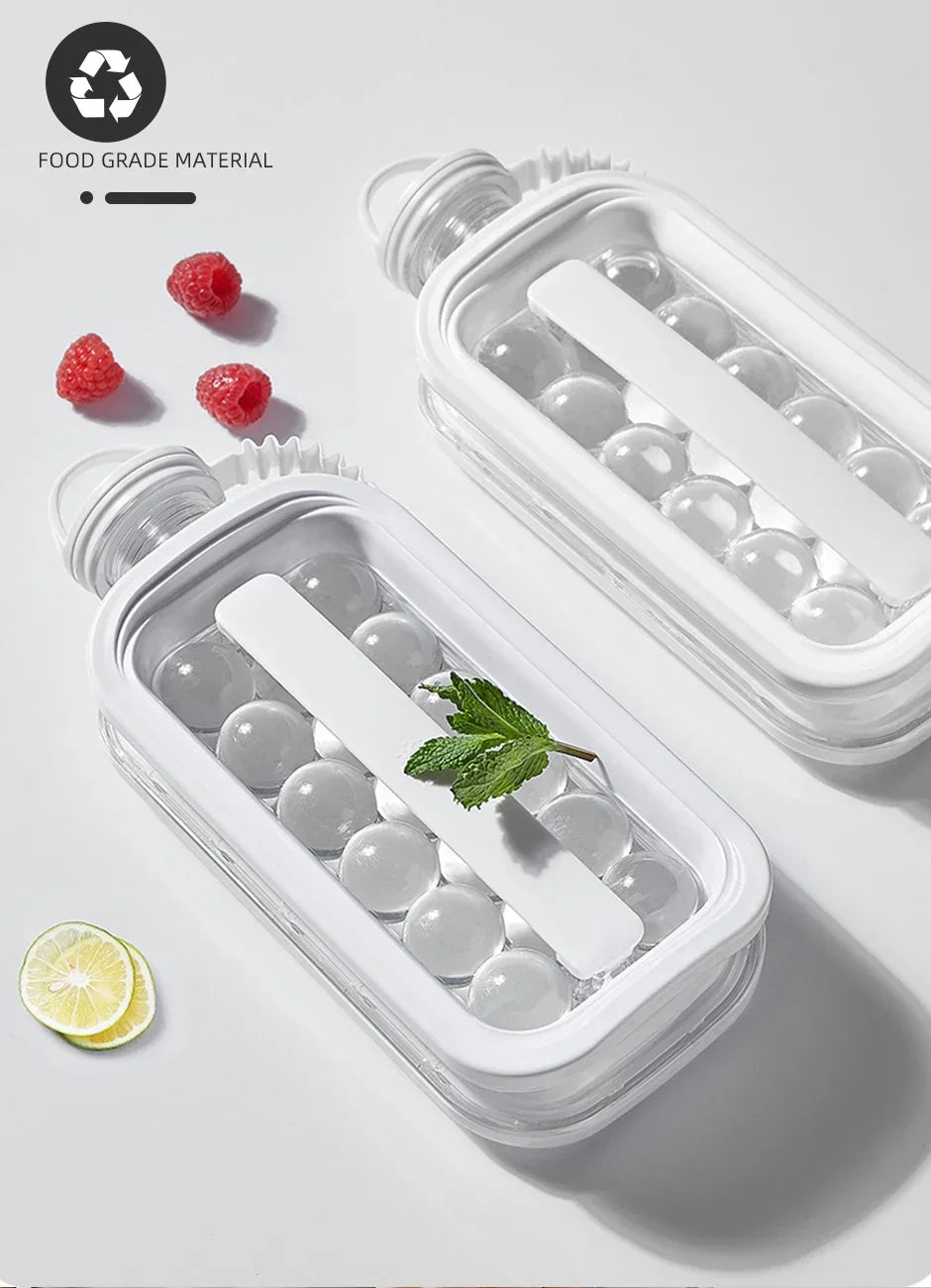 A clear plastic ice cube maker in a bottle design holds round ice cubes and is shown next to raspberries and a lemon slice.