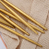 A set of matte gold stainless steel cutlery lying on a beige woven cloth.