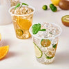 A glass of iced citrus drink in a clear plastic cup filled with ice, lime slices, and mint leaves.