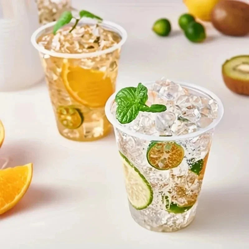 A glass of iced citrus drink in a clear plastic cup filled with ice, lime slices, and mint leaves.