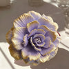 A purple silicone flower mold with gold accents, shaped like a ruffled bloom.