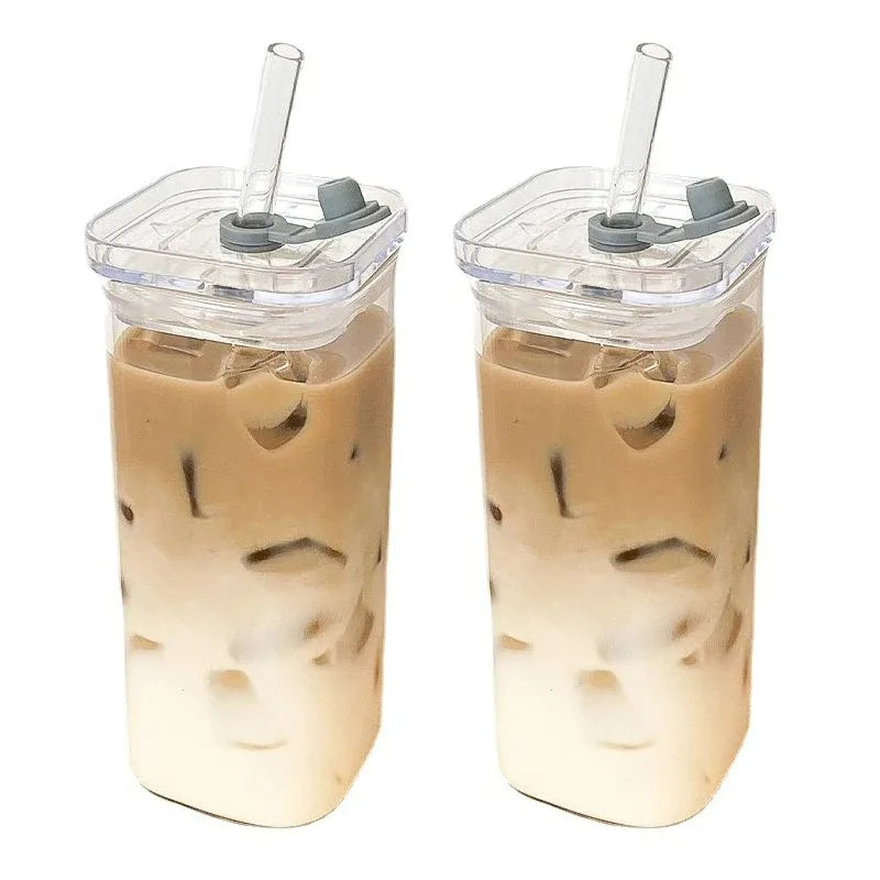 A tall glass cup filled with iced tea or a similar beverage, featuring ice cubes and a clear plastic lid with a straw.