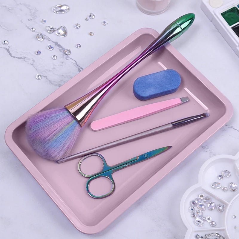 A pink tray holds various stainless steel professional nail art and dental tools including brushes and scissors.