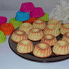 A collection of colorful silicone baking molds in various shades of pink, green, and orange arranged on a dark plate.
