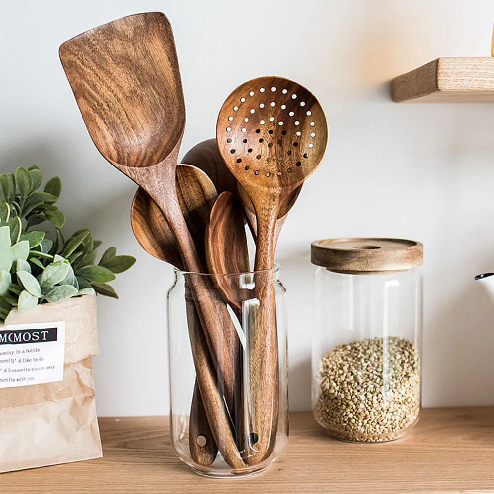Une collection d'ustensiles de cuisine en bois naturel, comprenant une spatule et une écumoire, stockés dans un bocal en verr