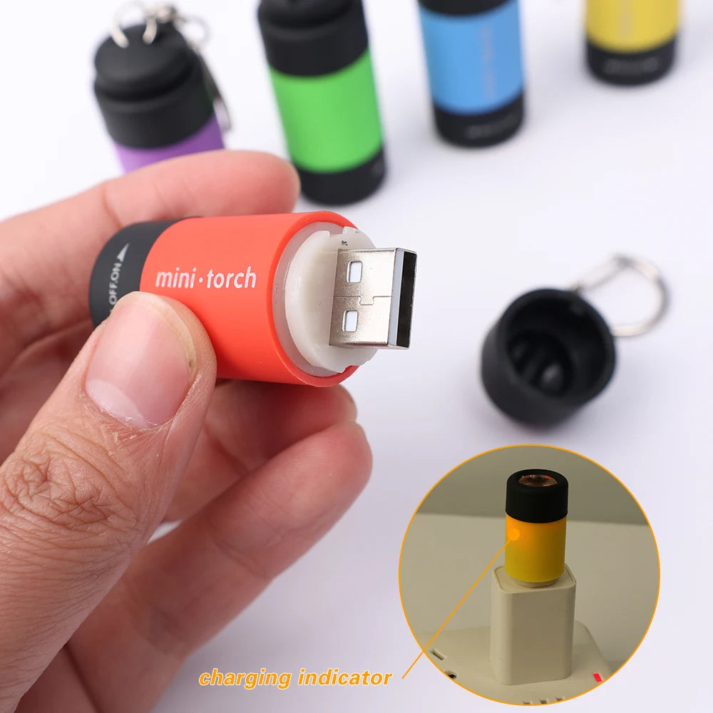 A hand holds an orange mini torch flashlight with a USB connector, showing the charging indicator on the device.