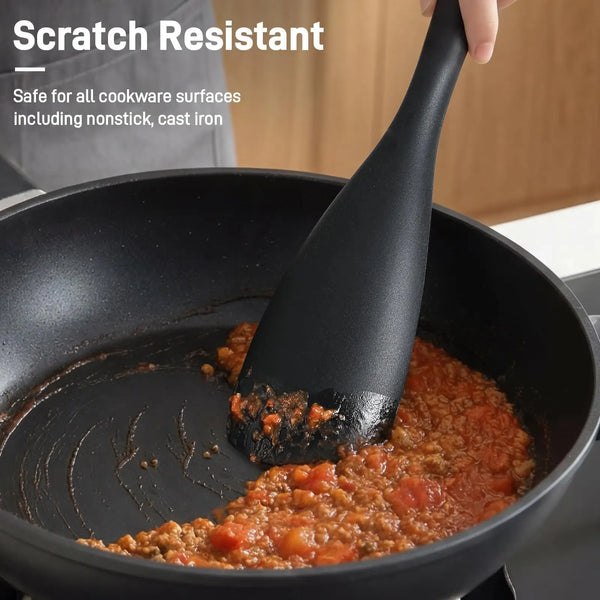 Eine Hand benutzt ein schwarzes Silikon-Kochwerkzeug, um Essen in einer schwarzen Antihaftpfanne zu rühren.
