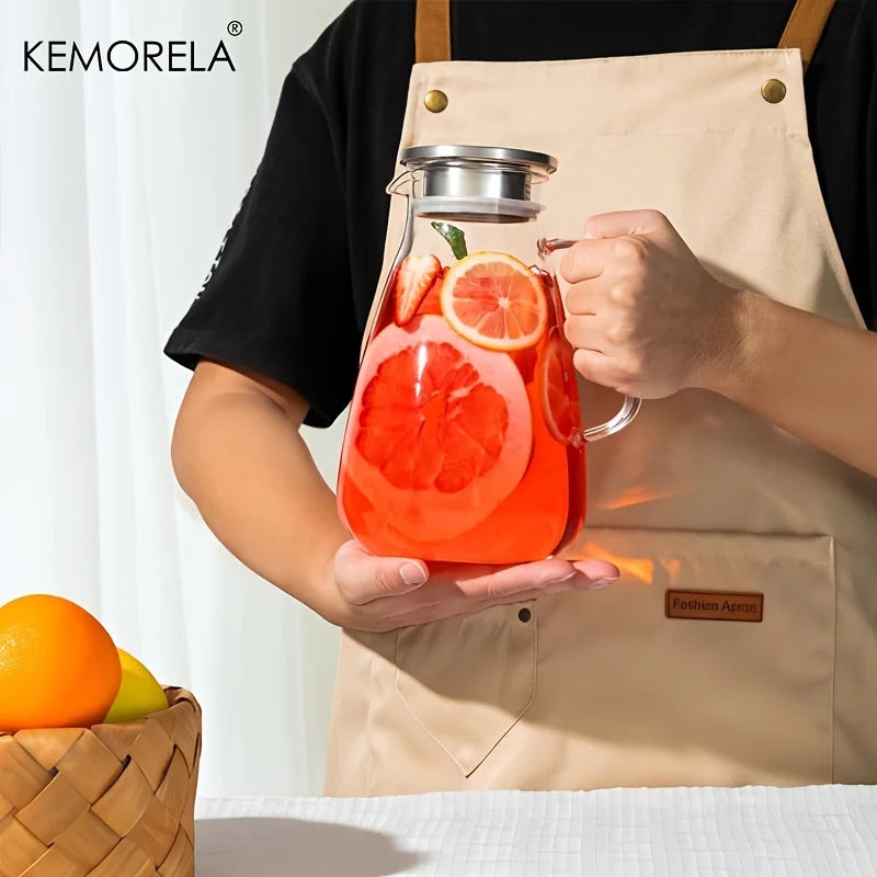 A hand holds a 2L glass pitcher filled with orange juice and garnished with citrus slices, set against a light background.
