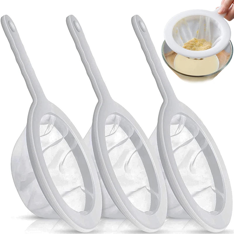 Un jeu de trois tamis en maille blanche et un tamis pour tamisage fin, montrés avec une petite quantité de matière.