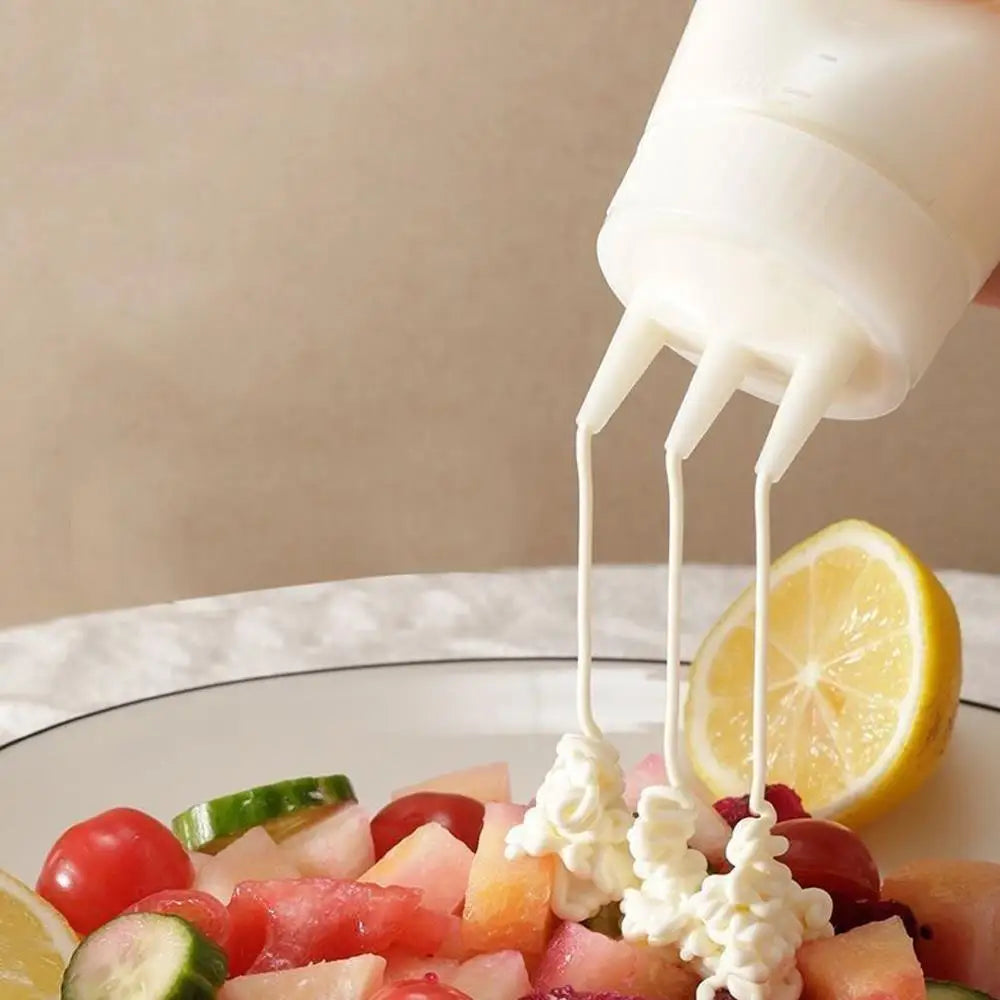 A squeeze bottle dispenses a white liquid onto a plate of fresh fruit and vegetables.