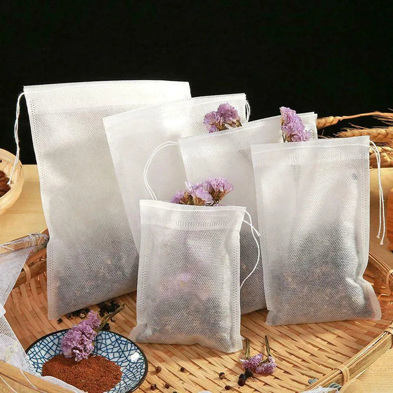 White mesh disposable tea filter bags with drawstrings filled with loose tea and spices