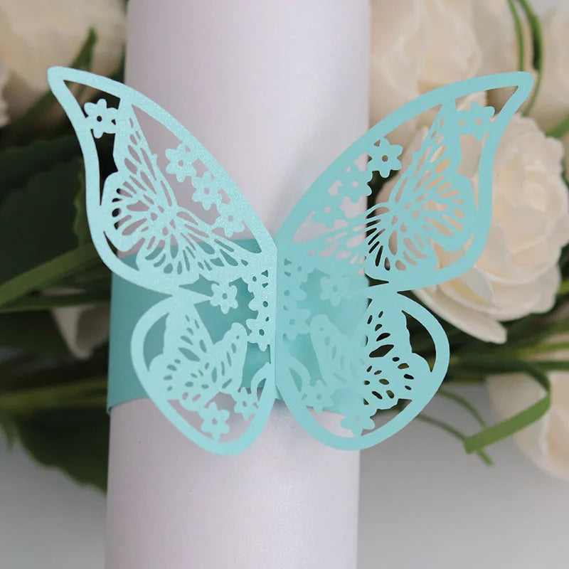 Light blue laser cut butterfly napkin rings displayed against a white background with white roses.
