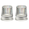 A pair of clear rotating whiskey glasses with multicolored vertical stripes and textured bases.
