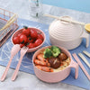 A pink microwave ramen cooking set in a pot with utensils and fresh ingredients on a blue cloth.