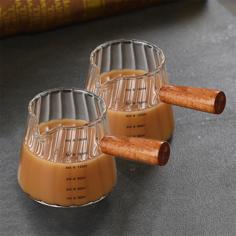 Clear glass espresso shot glasses with wooden handles, showing various liquid volumes.